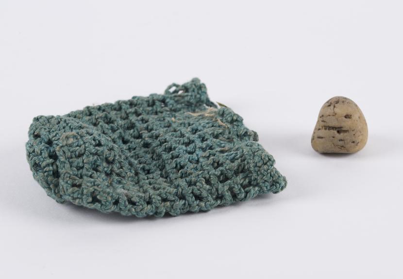 Blue crotcheted wool bag containing tooth-shaped stone