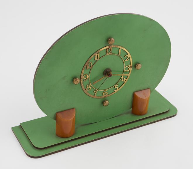 Plastic green, oval-faced clock, with brass circular dial