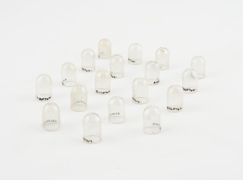 Eighteen glass domes, possibly covers for bottles