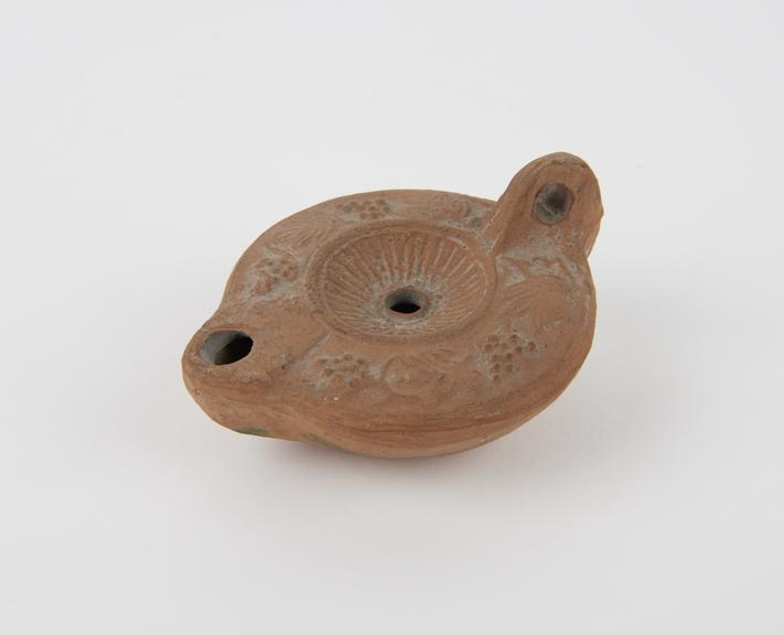 Roman terracotta oil lamp with raised pattern of vine leaves