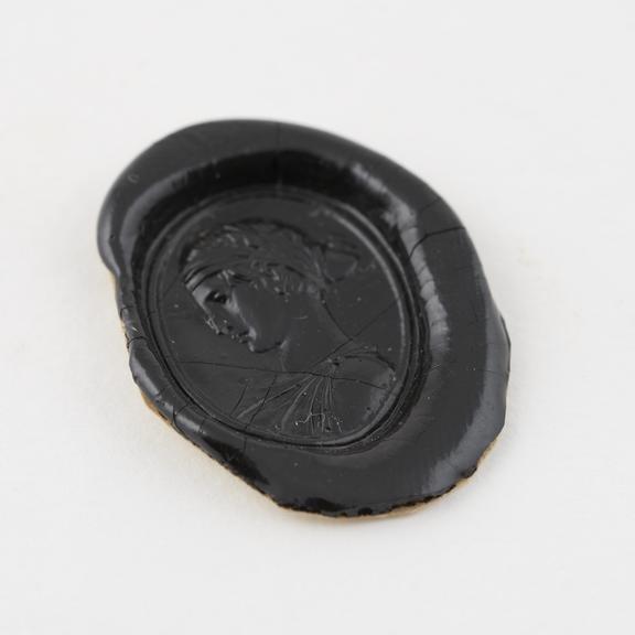 Seal of black shellac with oval stamp showing female head in