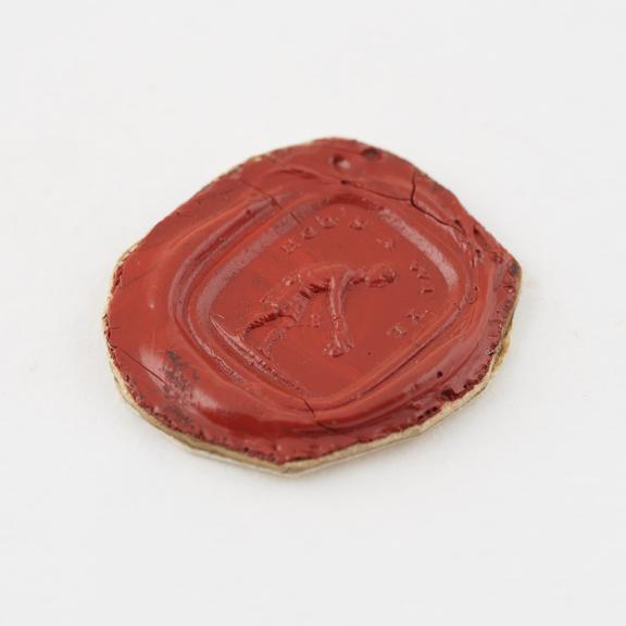 Roughly circular seal of red shellac with oblong stamp showing