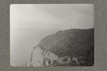 Untitled black and white photograph showing a mountainous view with tree covered