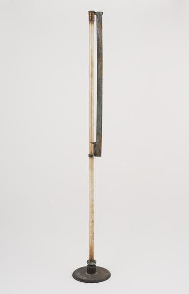 Long glass tube on stand with brass scale attached said to have