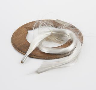 Wooden disc with centre cut out and sample of white hair