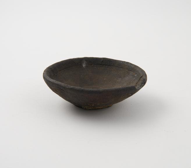 Black earthenware dish, no lip, marked Nasirabad