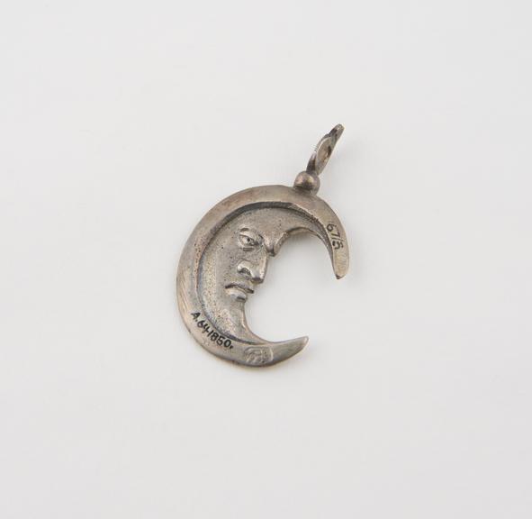 Silver amulet, in the shape of a crescent moon with a face