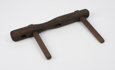 Wooden bar with 4 recatngular holes and two pegs.