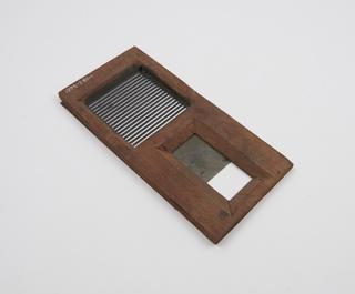 Wooden grid slide, with rectangular hole partly covered by metal grill attachment