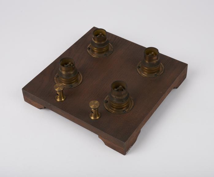 4 light bulb sockets mounted on mahogany base