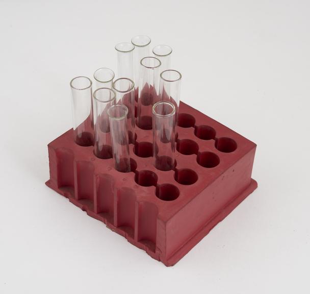 Rubber block holding 11 glass test-tubes for testing heparin