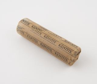 Cylindrical stick of explosive substitute in brown paper wrapper with black printing and trade name patterning