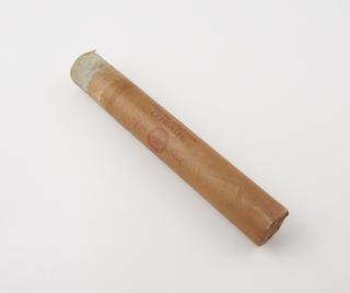 Cylindrical stick of explosive substitute in brown paper wrapper with red printing