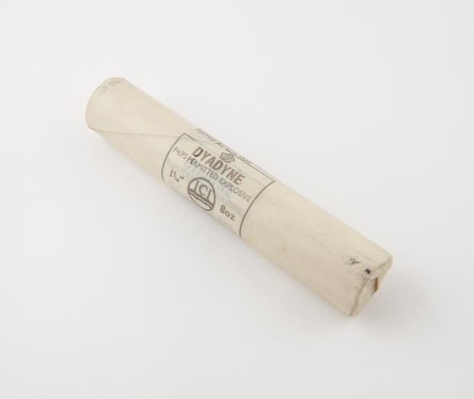 Cylindrical stick of explosive substitute in white waxed paper