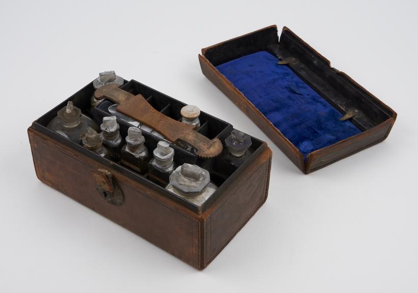 Rectangular leather medicine chest lined with leatheretete and velvet, contains 15 glass bottles (14 labelled), brass scales, English, 1801-1900