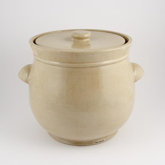 An empty, glazed earthenware crock, with handles and a lid