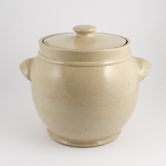 An empty, glazed earthenware crock, with handles and a lid