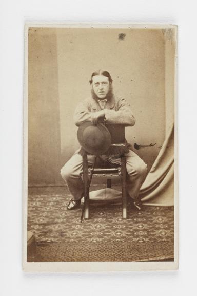 A Carte de visite portrait of a man sat on a backwards chair