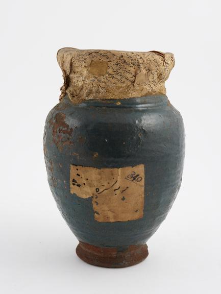 Blue glazed earthenware jar with rim wrapped in newspaper