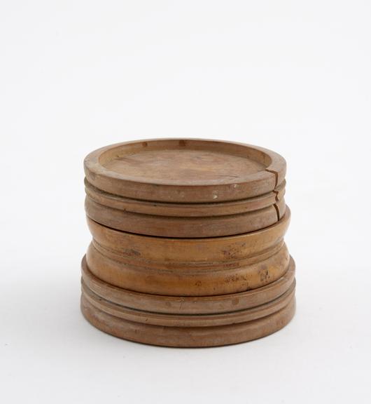 Three round wooden pill finishers with grooved exterior sides