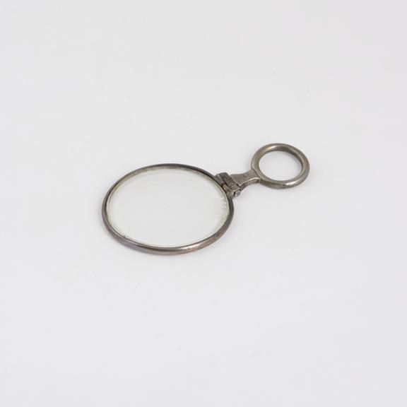 Small hand magnifying glass, with hinged loop for attachment