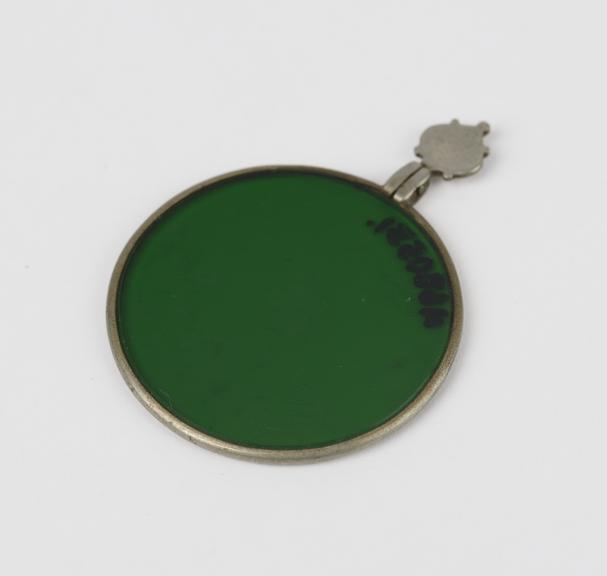 Dark green glass lens mounted in silver plated ring with handle