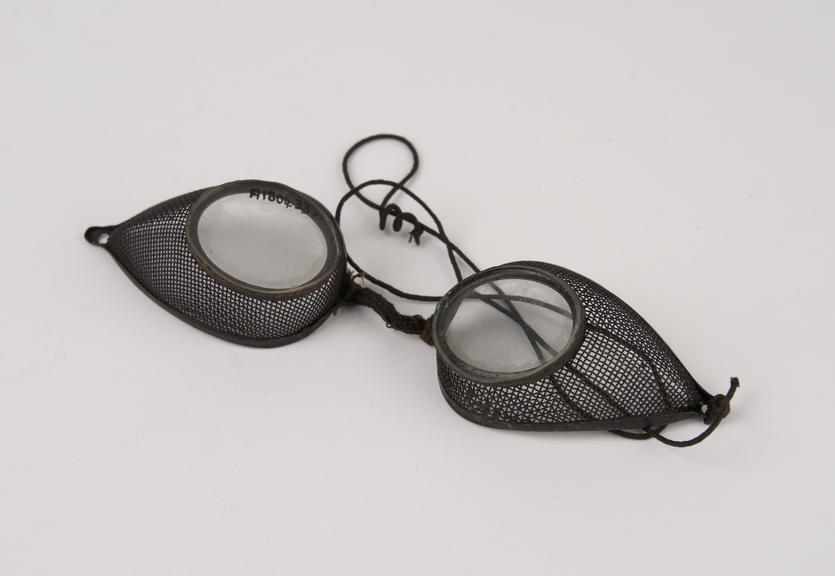 Pair of metal rimmed oval spectacles, with wire mesh protectors