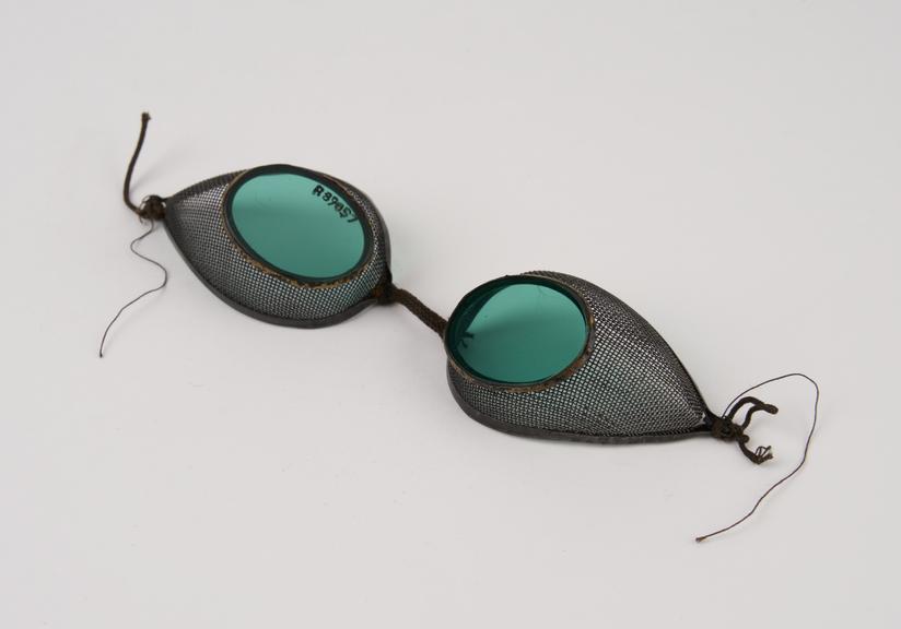 Pair of metal-rimmed oval green glass spectacles with wire mesh