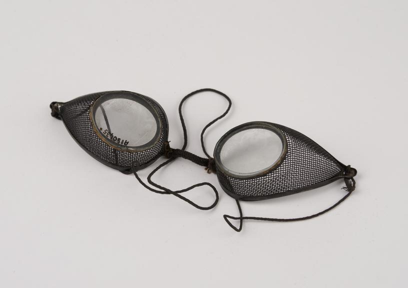 Pair of metal rimmed oval spectacles, with wire mesh protectors