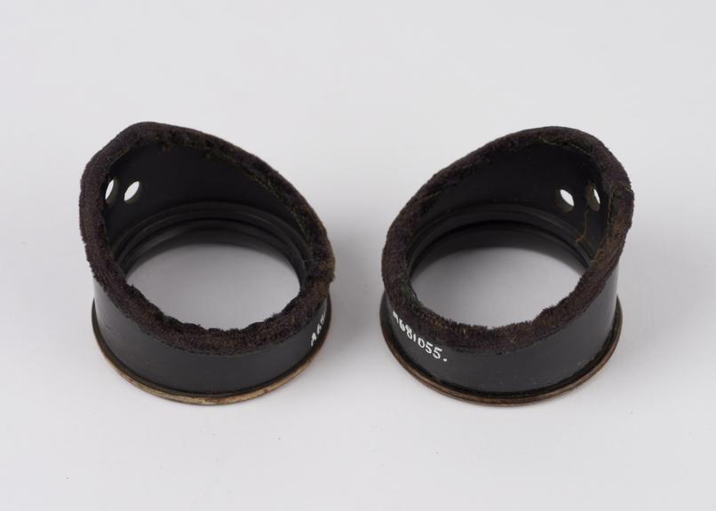 2 cylindrical bakelite(?) eye-shields perforated for