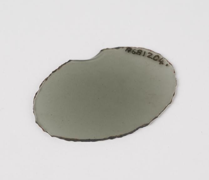 Lens, roughly cut oval shape, glass, chipped, from spectacles