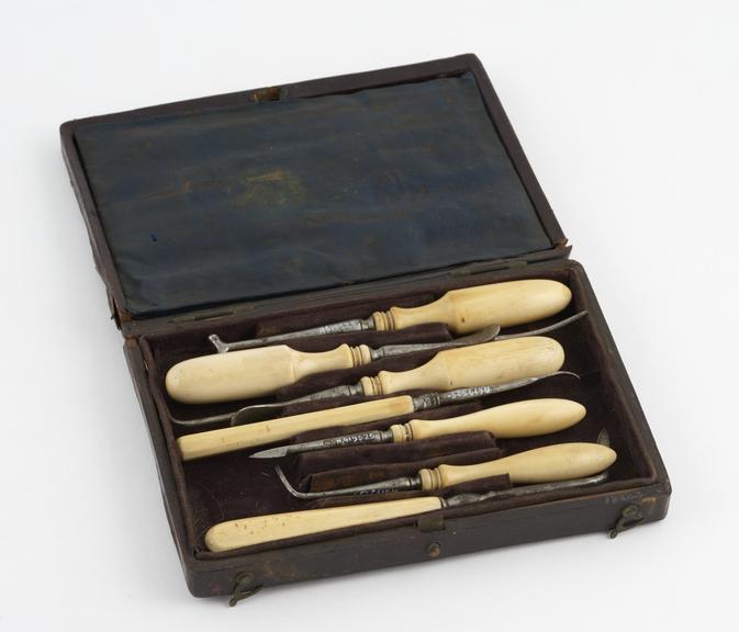 Dental instrument set in rectangular maroon tooled leather