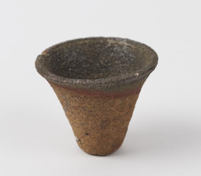 Small funnel shaped earthenware crucible with hole at end