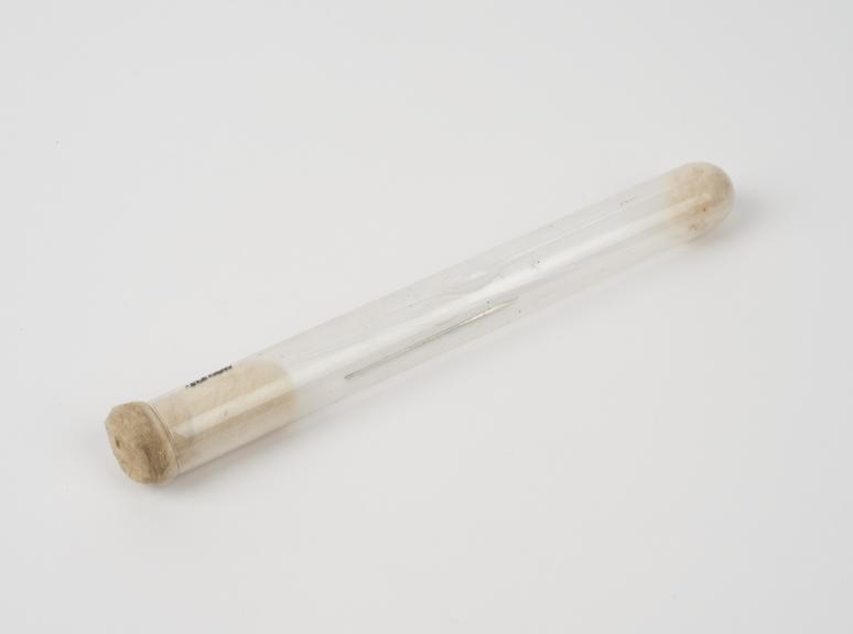 Clear glass test tube containing needle with triangular point