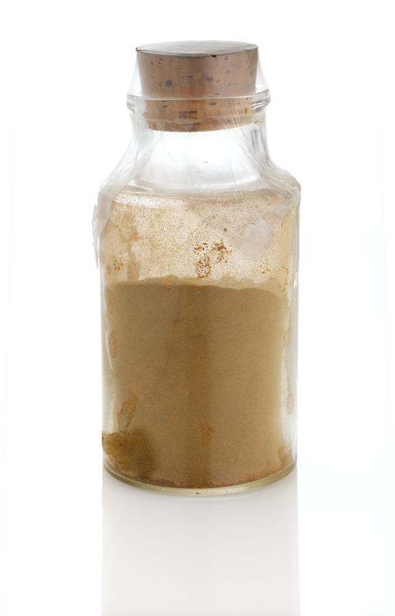 Corked specimen bottle containing brown powder, "kina"