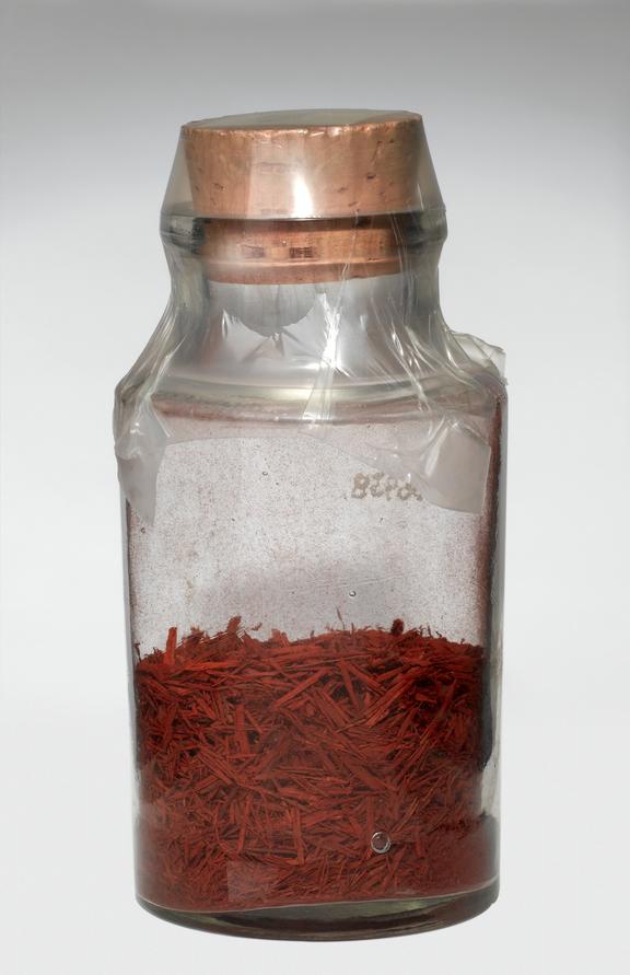 Corked specimen bottle containing shredded red plant(?)