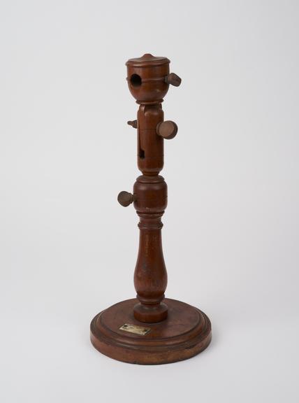 Tube holder, wood with metal weight, maker's name obscured