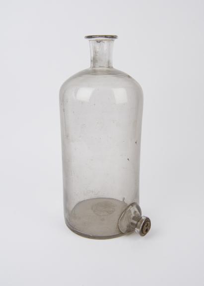 Bottle, clear glass, with tubulure near base, by Leune, Paris