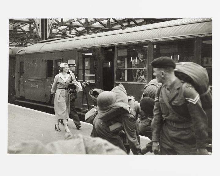 Smart couple and soldiers on train platform