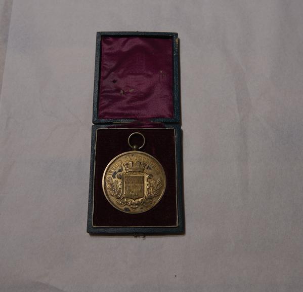 Gold-Coloured Circular Metal Medal, in Green and Red Rectangular Case, Won by James Moore