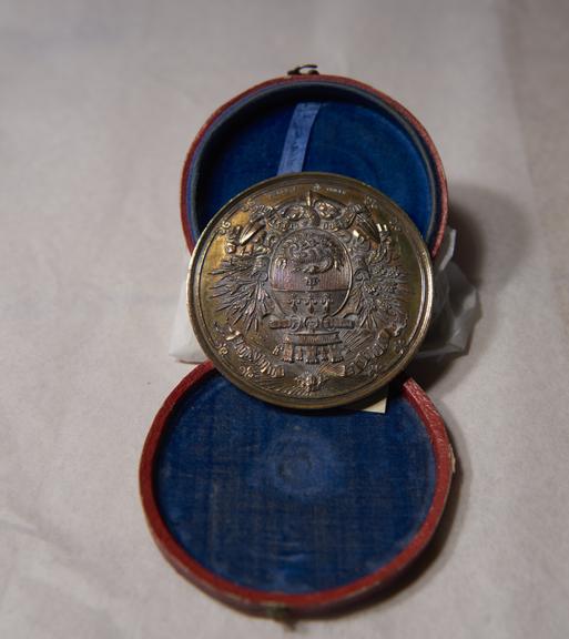 Gold-Coloured Circular Metal Medal, in Red and Blue Circular Case, Won by James Moore