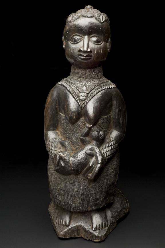 Carved ebony filigree of seated woman suckling an infant