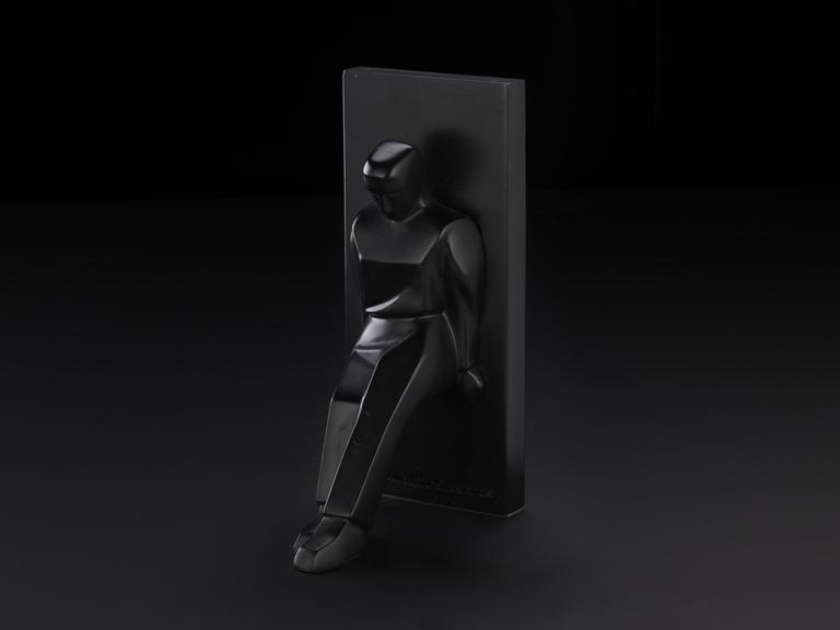 Black bookend of a figure leaning against a block. Designed by Chris Collicot for Kikkerland