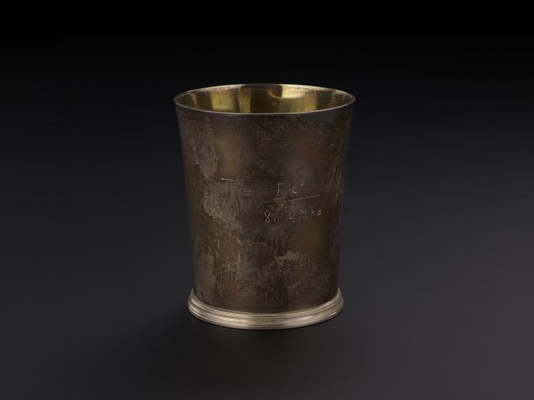 A silver beaker engraved with an equation