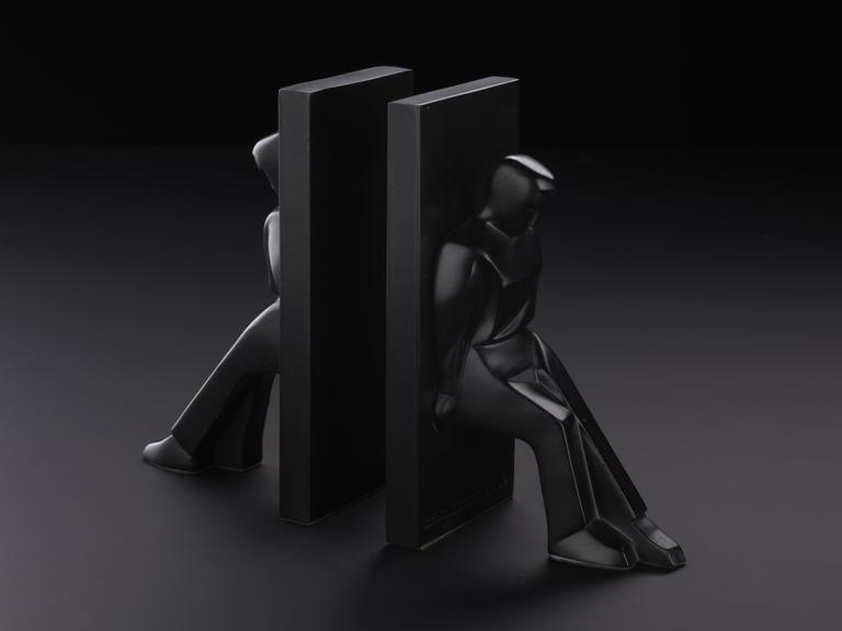 Black bookend of a figure leaning against a block. Designed by Chris Collicot for Kikkerland