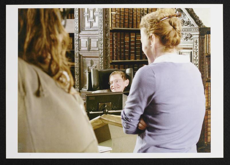 Framed photograph of actor playing Stephen Hawking in library (color photograph; frame)