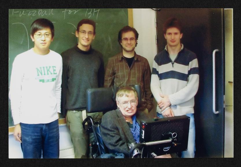 Framed photograph of Stephen Hawking with four students in his office