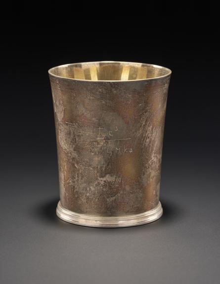 A silver beaker engraved with an equation