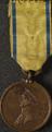 Circular bronze medal with yellow and blue ribbon