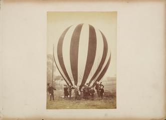 Photograph, balloon before flight being held by young men and boys